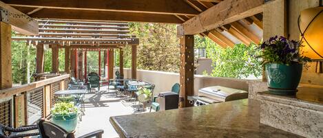 Eine Außenpatio-Terrasse mit Holz-Pergola, Sitzgelegenheiten und einem Grill.