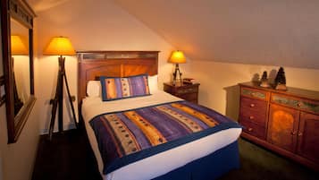 Un dormitorio ordenado con cama, dos lámparas de noche, un tocador y un espejo.