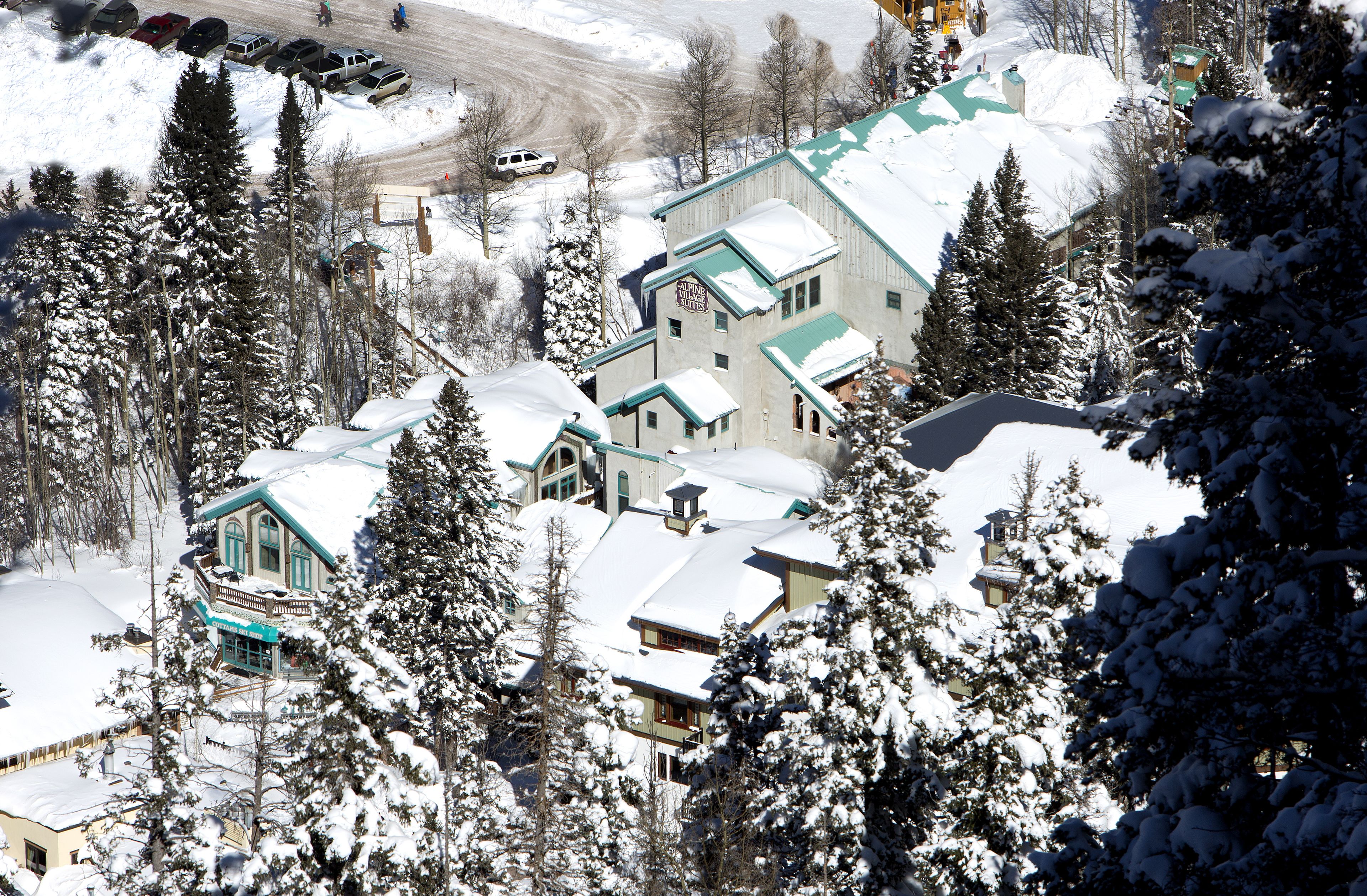 Un edificio imbiancato dalla neve, con numerose finestre e un tetto verde, circondato da alberi carichi di neve.