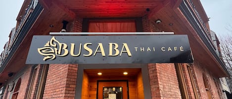 The exterior of Busaba Thai Cafe with a prominent sign, a wooden facade, and a sloped roof.