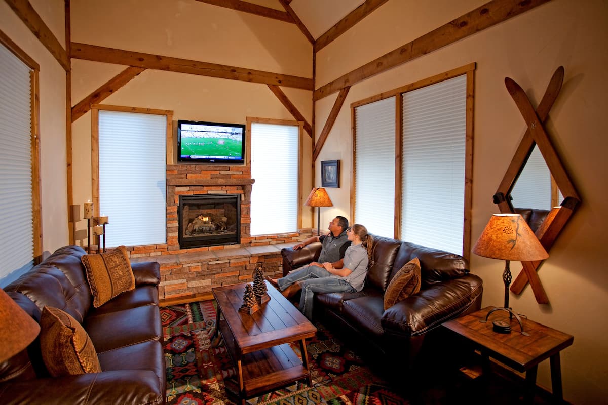 A cozy living room with a fireplace, leather sofas, and a television.