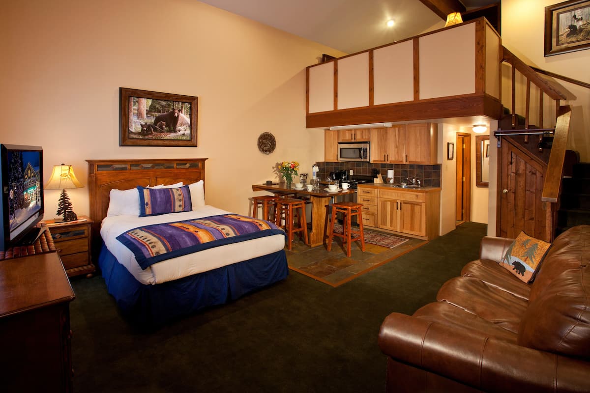 A bedroom with a bed, a wooden headboard, a nightstand, a TV, and a desk with a chair.