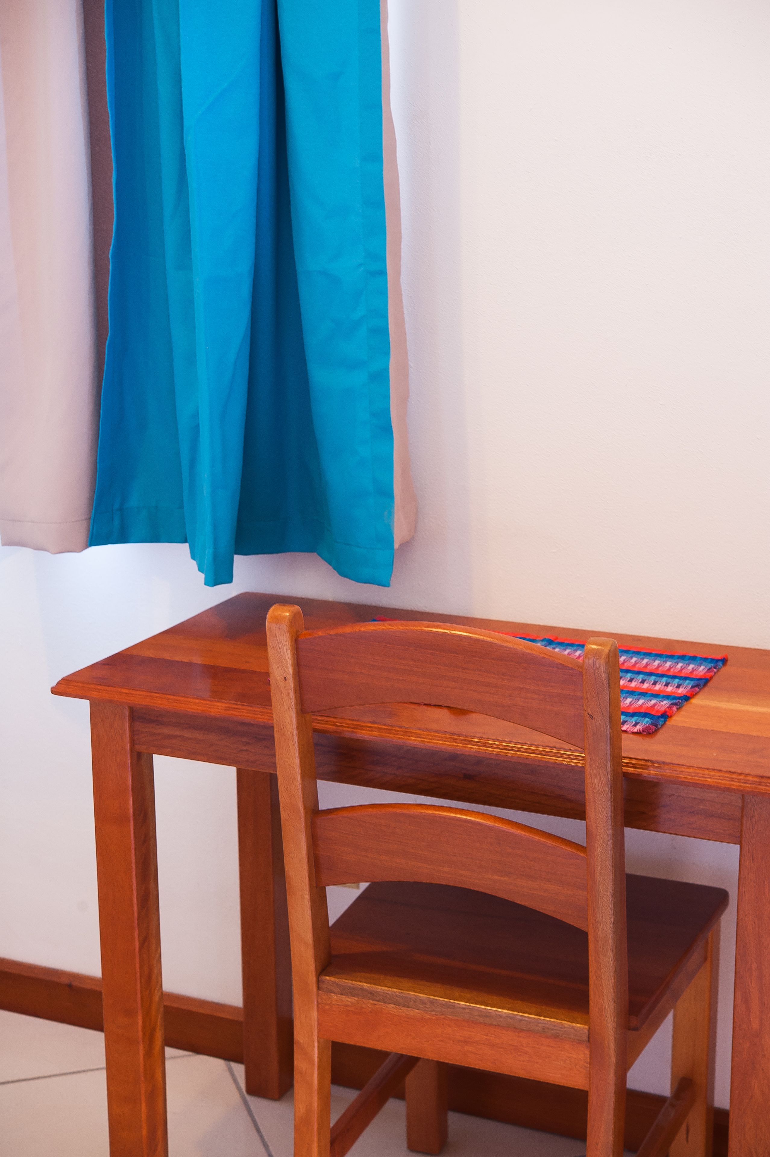 Una silla de madera con asiento y respaldo trenzados, ubicada junto a una mesa de madera.