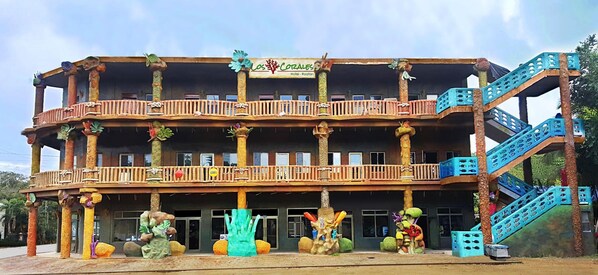 Un edificio de varios pisos con temática tropical, que cuenta con balcones y una escalera.