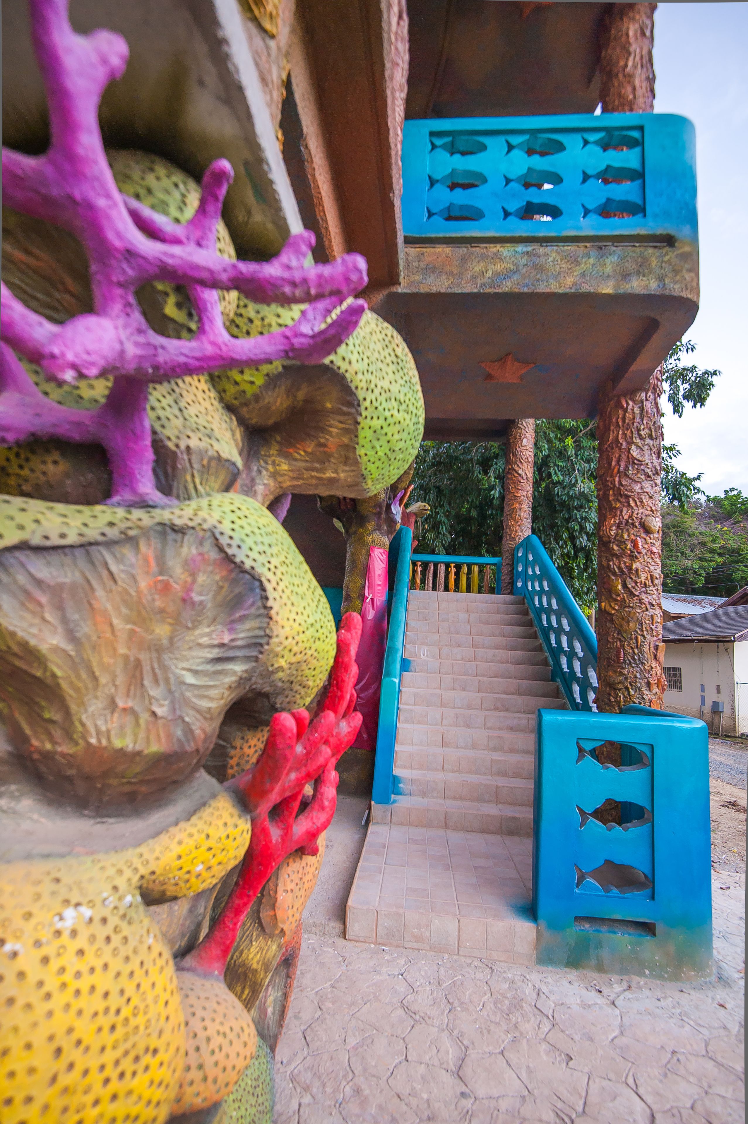 A staircase with a blue railing and a blue door with fish cutouts.