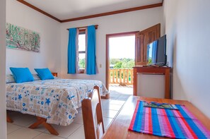 Un dormitorio con cama, televisión y balcón con vistas.