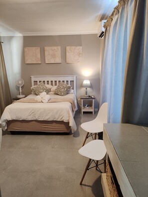 A bedroom with a bed, bedside table, lamp, and a chair.