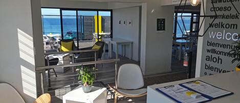 Un espacio de oficina moderno con vistas al mar, un mostrador de recepción y zonas de estar.