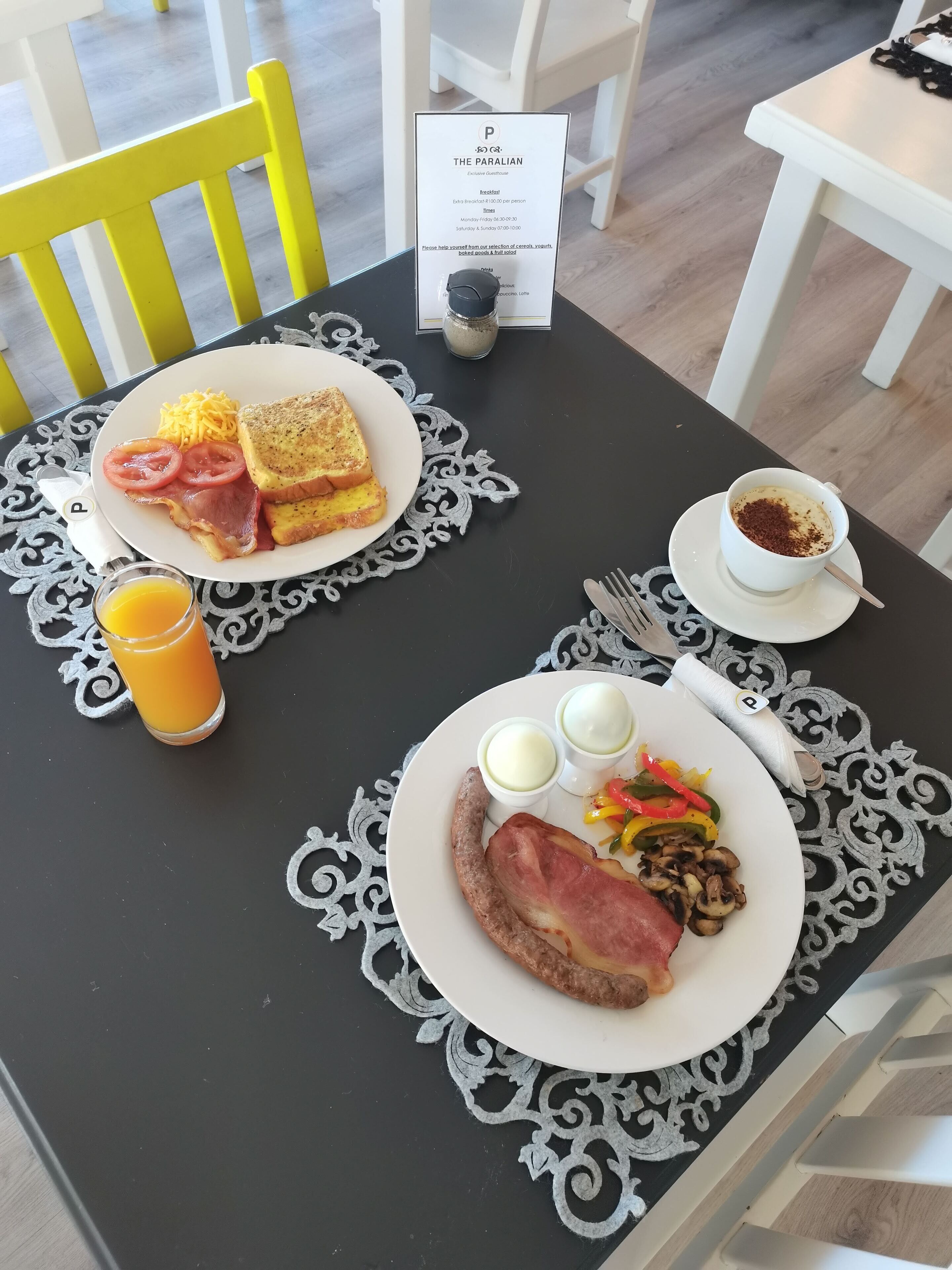 A breakfast setting with two plates of food, a coffee cup, and a menu.