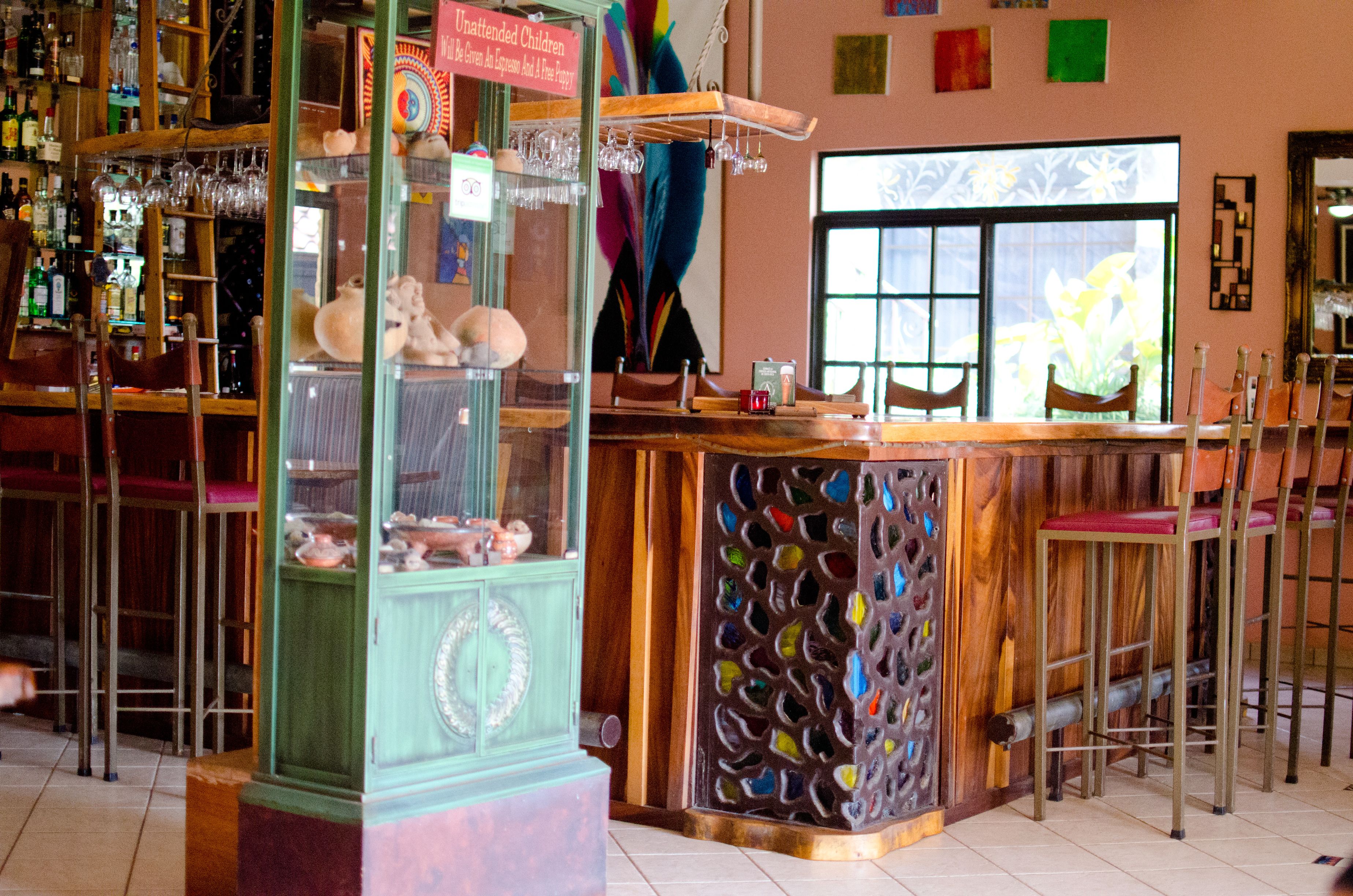 A bar with a wooden counter, stools, and a display case with various items.