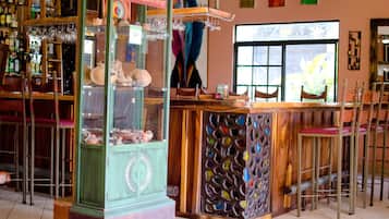 A bar with a wooden counter, stools, and a display case with various items.