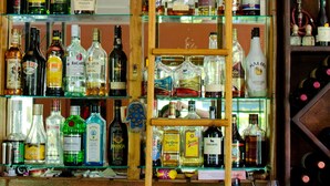 Um bar com prateleiras repletas de garrafas de bebidas diversas.