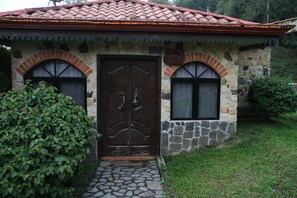 A stone building with a tiled roof, a central door, and two windows on either side.