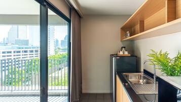 A modern kitchen with a built-in sink, wooden shelves, and a view of a cityscape through a large window.