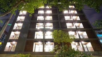 A multi-story building with balconies and windows illuminated at night.