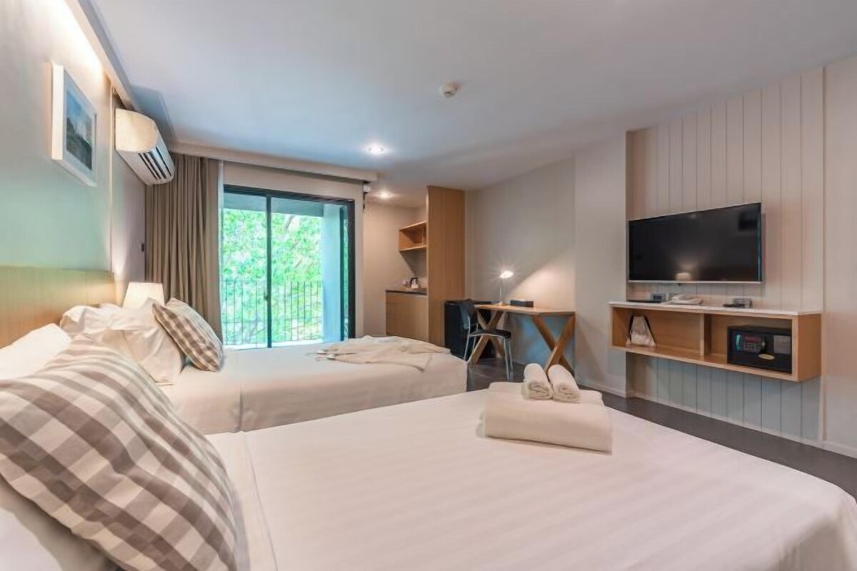 A hotel room with two beds, a television, and a desk with a chair.