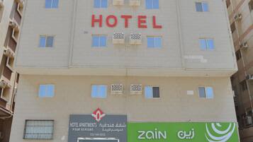 A hotel building with a sign indicating 'HOTEL APARTMENTS FOUR SEASONS'.