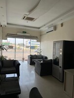 A reception area with a large window, a seating area with sofas, and a refrigerator.