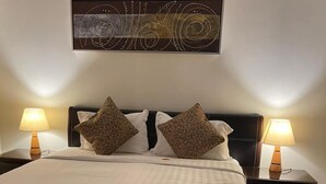 A neatly made bed with a patterned bedspread, two pillows, and two bedside lamps. - Binayat Hama Serviced Apartments (Al Jubail)