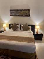 A neatly made bed with a patterned bedspread, two pillows, and two bedside lamps.