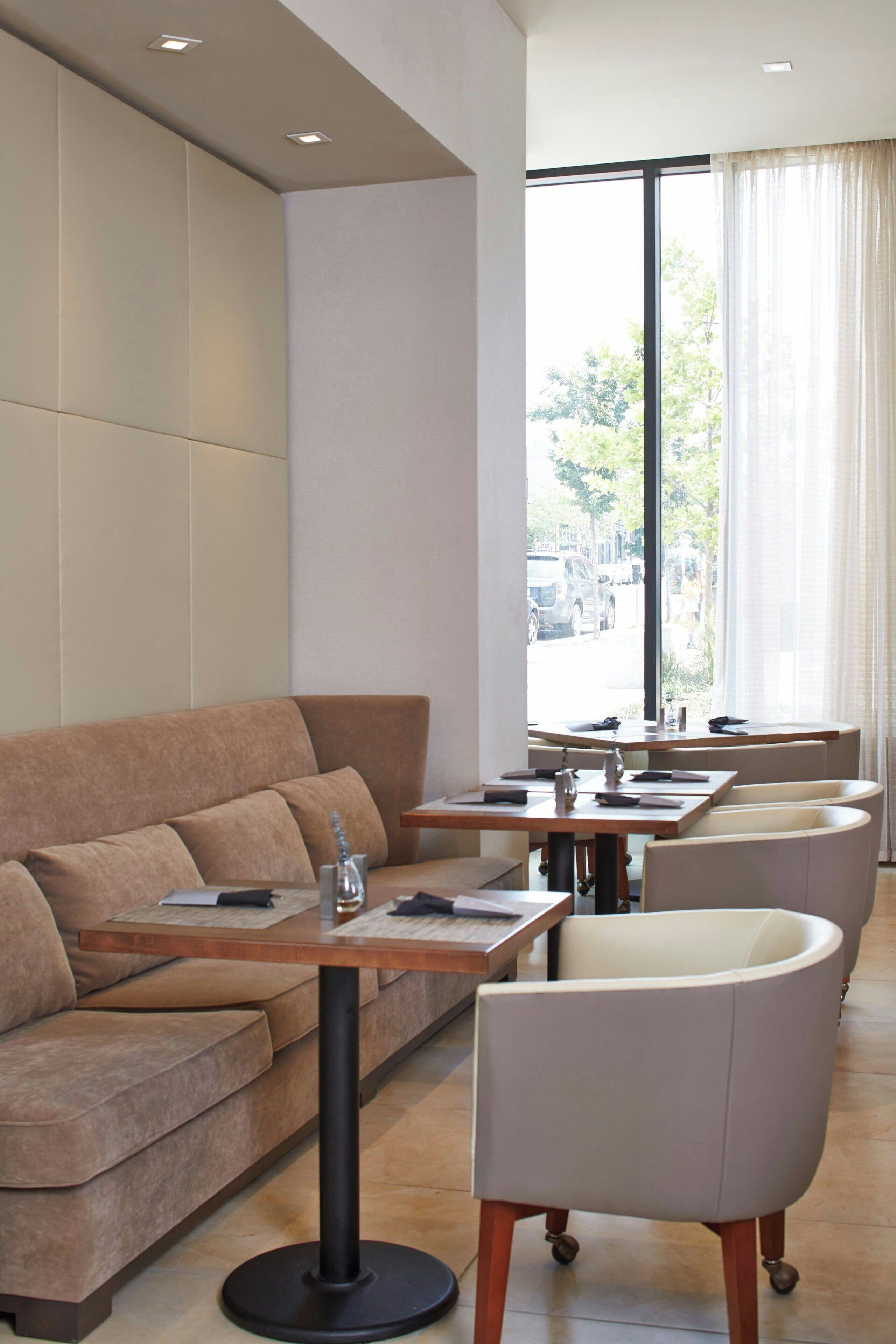 A modern interior with a sofa, dining tables, and chairs.