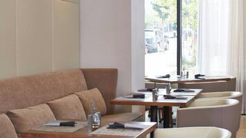 A modern interior with a sofa, dining tables, and chairs.