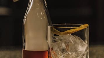 Una botella de líquido ámbar junto a un vaso con cubitos de hielo.
