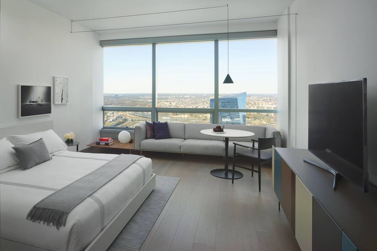 Une chambre d’hôtel moderne avec un grand lit, un canapé, une petite table et un téléviseur.