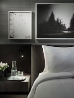 Quarto moderno com uma cama, uma mesa de cabeceira com um vaso de flores, uma moldura com uma fotografia e uma moldura com uma paisagem.