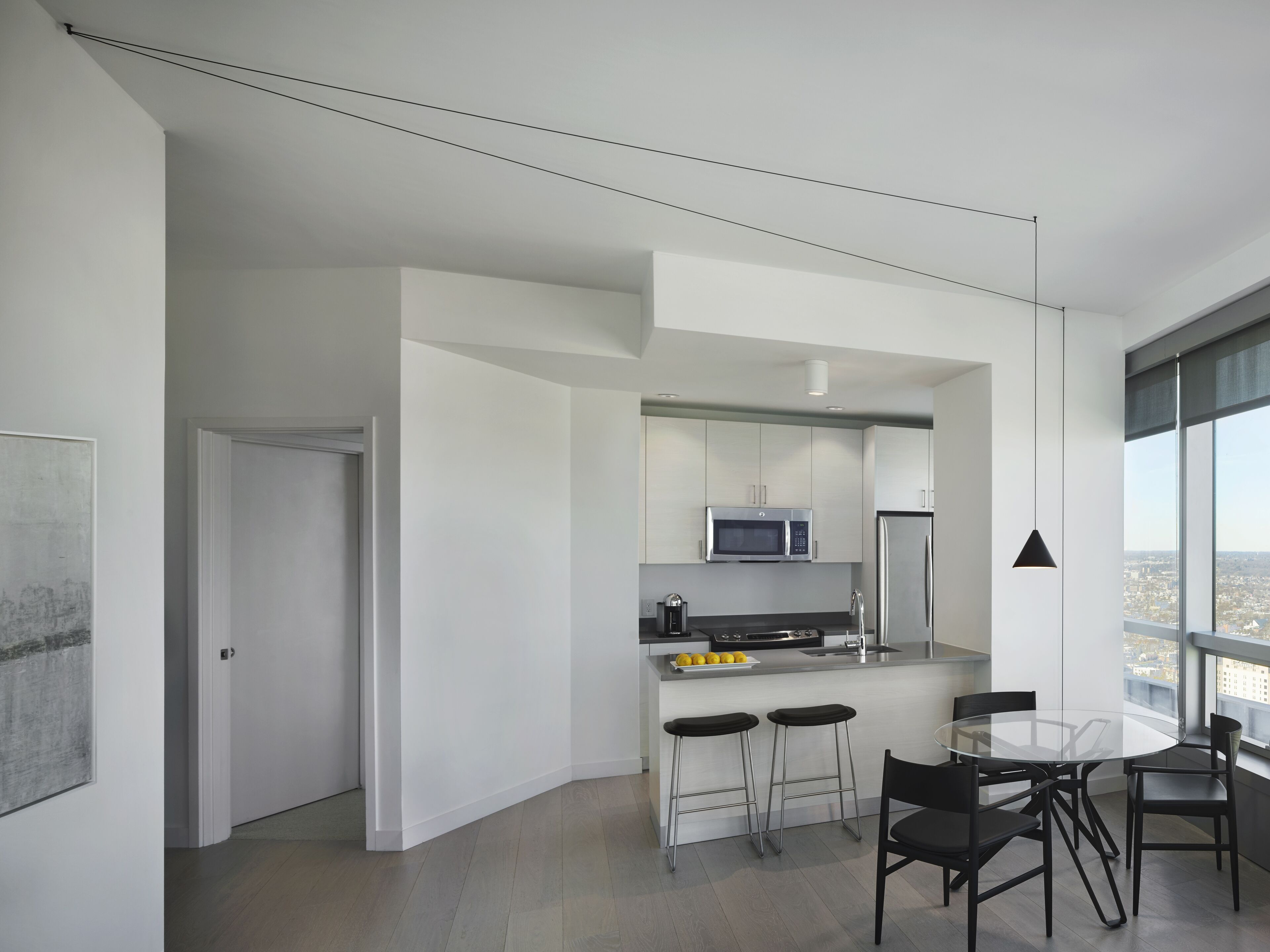 A modern kitchen with a central island, bar stools, and a dining table with chairs.