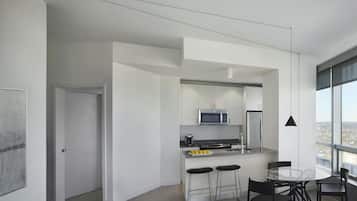A modern kitchen with a central island, bar stools, and a dining table with chairs.