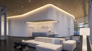 A modern lobby with a curved reception desk, a sectional sofa, and a minimalist decor style. - AKA University City (Philadelphia)
