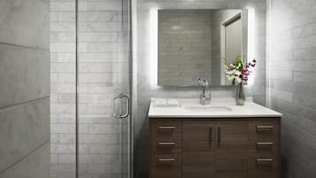 A modern bathroom with a marble shower, a large mirror, a wooden vanity, and a vase with flowers.