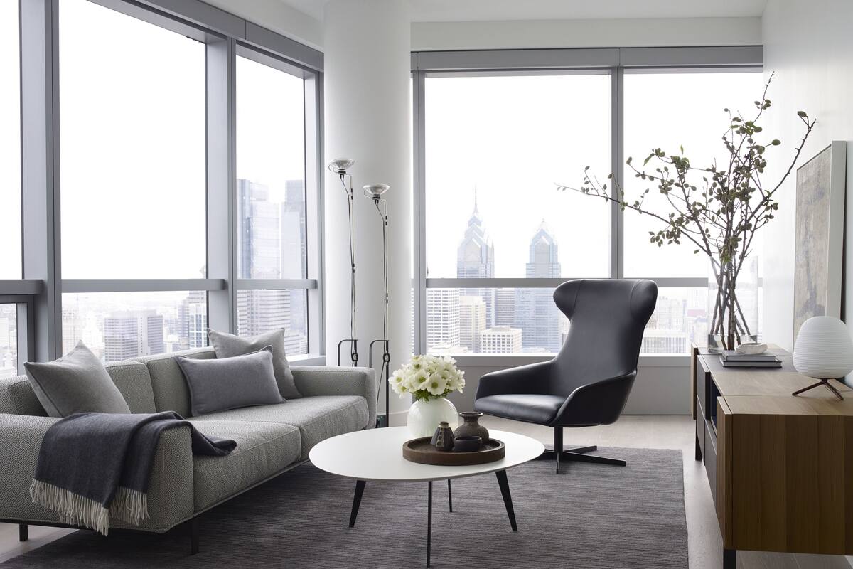 Un salon moderne avec un canapé gris, un fauteuil noir et une table basse ronde.