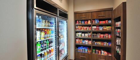 A refrigerated beverage display and a pantry stocked with snacks and beverages.