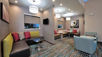 Moderni hotellihuone, jossa on sohva, nojatuoli ja pieni pöytä.
