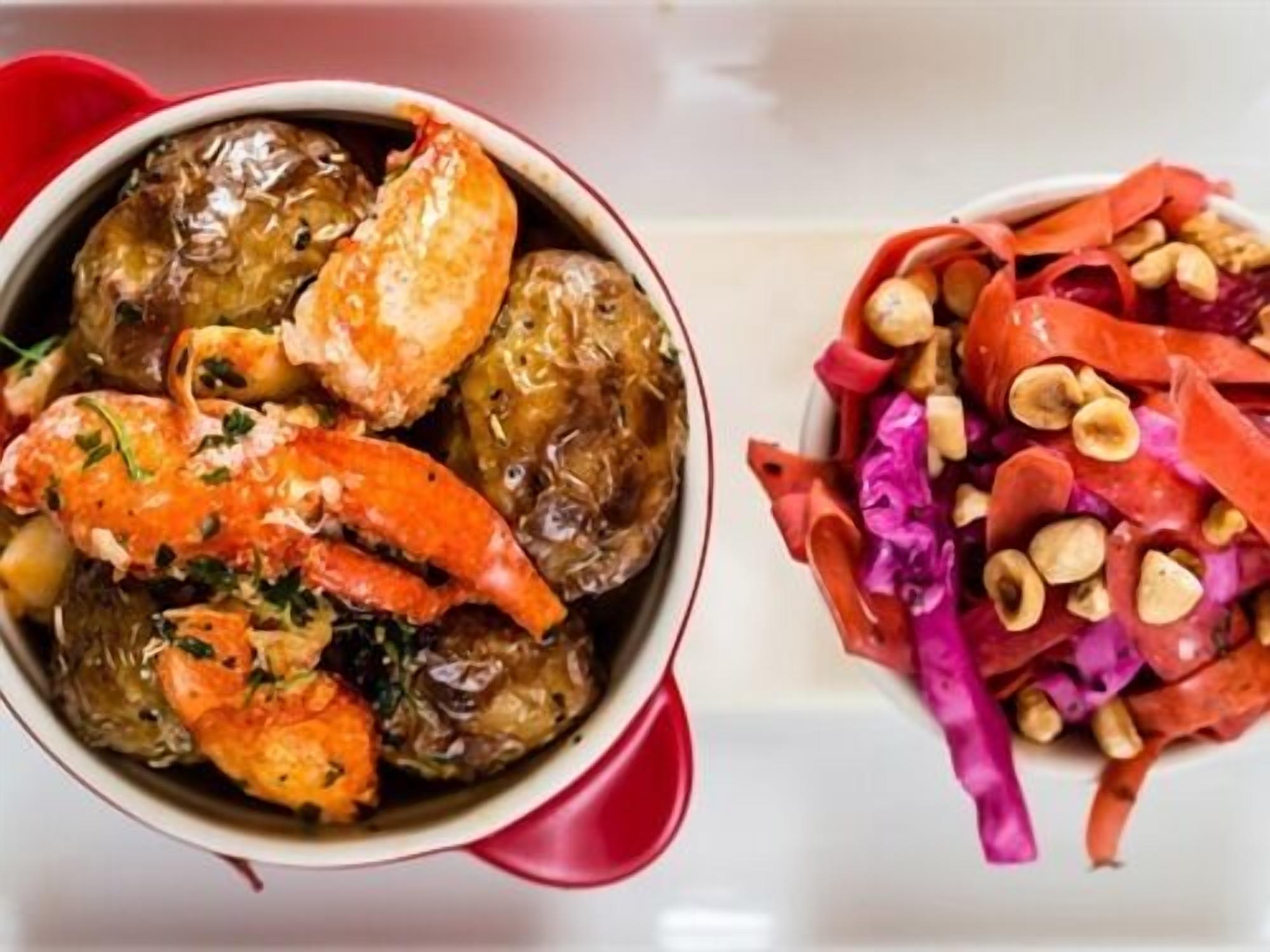 A bowl of cooked vegetables and a side salad with nuts.