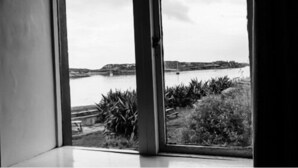 A room with a large window overlooking a body of water and distant land. - The Beach Day's Bar & B&B (Inishbofin)