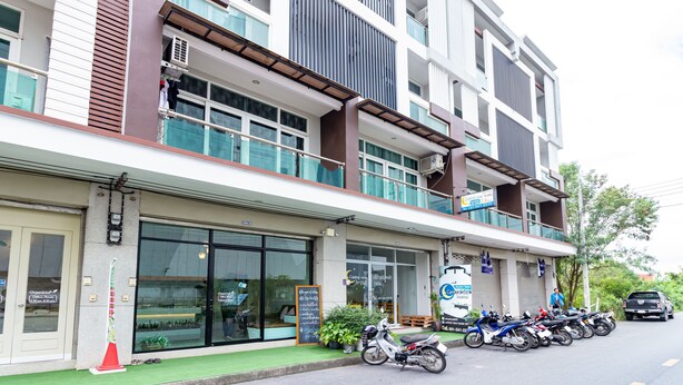 Un bâtiment moderne à plusieurs étages, doté de grandes fenêtres et d’un espace de stationnement pour motos.