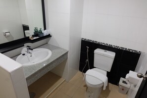 A bathroom with a white sink, black and white tiled walls, a toilet, and a trash bin. - Wisdom Residence (Hat Yai)