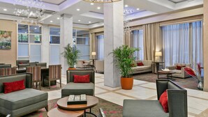 A spacious lobby with multiple seating areas, including sofas and armchairs, a large chandelier, and potted plants. - Sonesta Hotel Baltimore Inner Harbor (Baltimore)