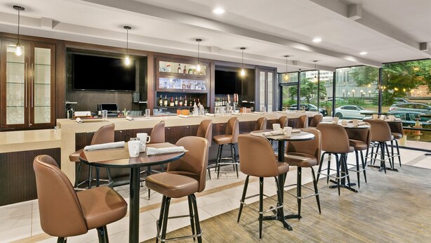 A modern bar area with a counter, seating, and a large TV screen. - Sonesta Hotel Baltimore Inner Harbor (Baltimore)