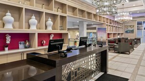 A hotel reception area with a modern design, featuring a reception desk, computer monitors, and a seating area with sofas and a coffee table. - Sonesta Hotel Baltimore Inner Harbor (Baltimore)