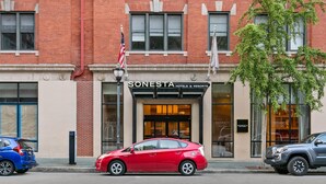 A red car parked in front of a brick building with a sign reading "SONESTA HOTELS & RESORTS". - Sonesta Hotel Baltimore Inner Harbor (Baltimore)