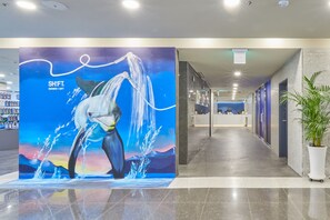 A hotel corridor with a large mural of a whale and the text "SHIFT SHOWER + GIFT". - Kolon Seacloud Hotel (Busan)