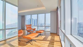 Un espacio de oficina moderno con ventanas amplias, suelo de madera y sillas color naranja.
