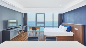 Et moderne hotelværelse med en stor seng, et skrivebord, en stol og et fjernsyn.