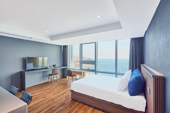 A modern hotel room with a large bed, a desk, and a TV.