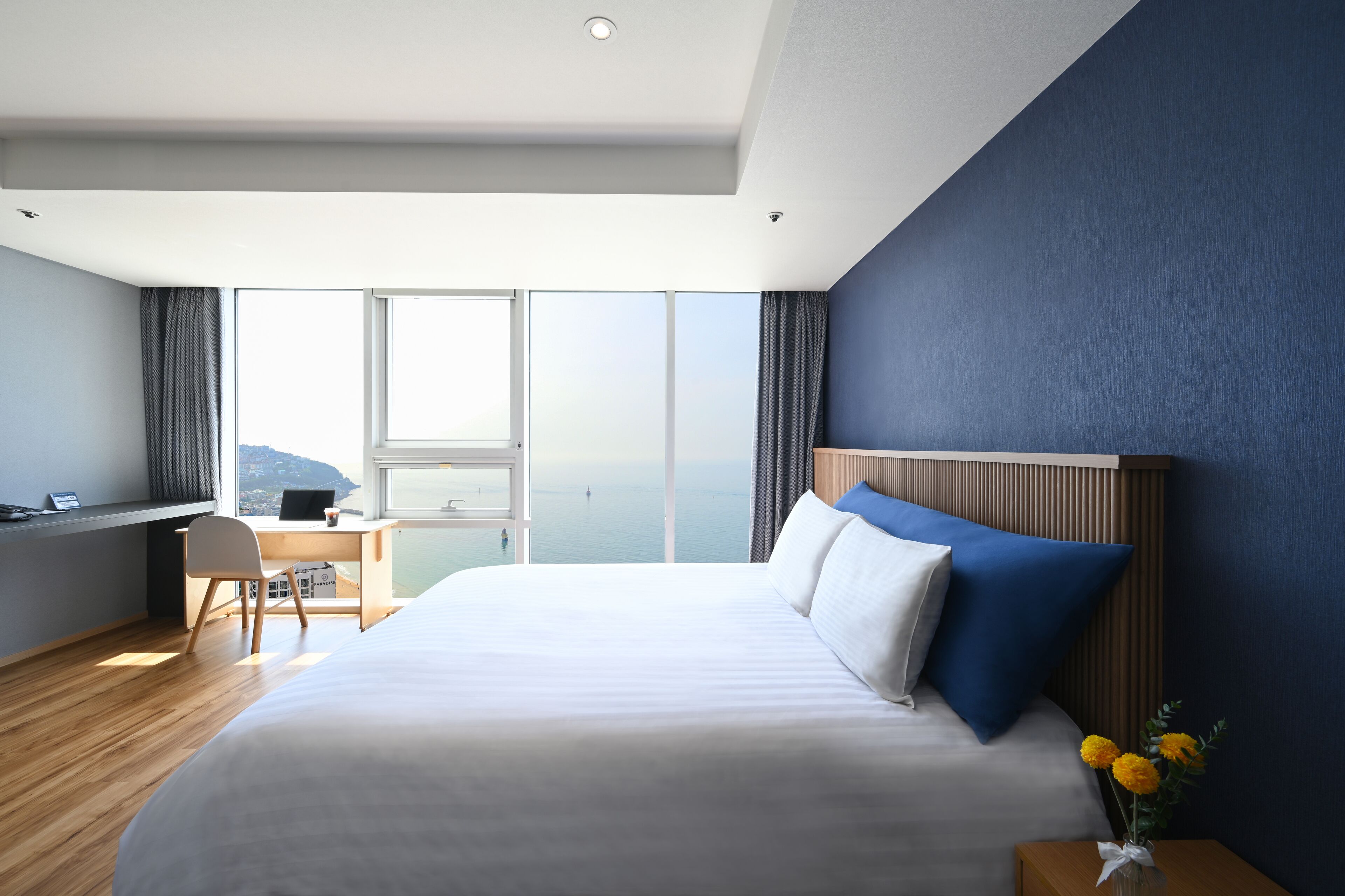 Ein Hotelzimmer mit einem großen Bett, einem Schreibtisch und Blick aufs Meer.
