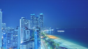 A coastal cityscape at night with high-rise buildings, a beach, and a marina. - Kolon Seacloud Hotel (Busan)